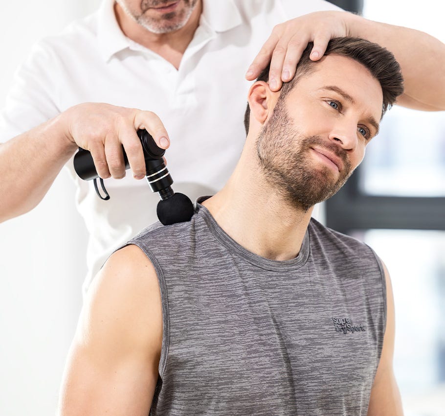 Physiotherapie in der Anwendung mit einer Vibrationsmassagepistole